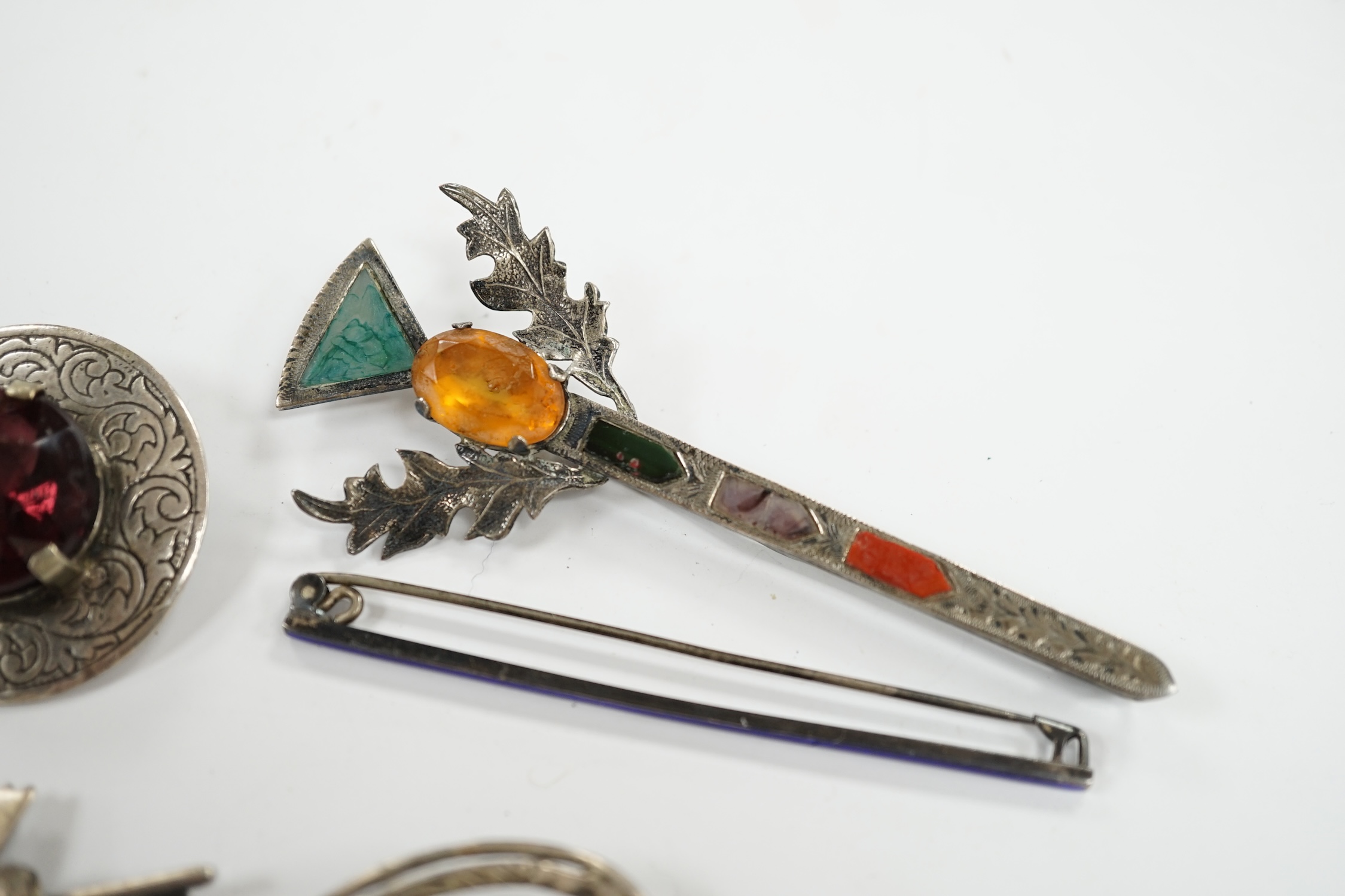 A 1950's Scottish silver, gem and Scottish hardstone set brooch, 91mm, together with six other brooches including four sterling and one silver. Condition - fair